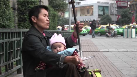 A-blind-man-plays-music-along-a-street-in-modern-China