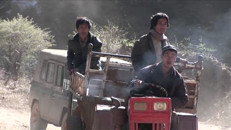 Men-drive-a-primitive-tractor-across-a-rural-landscape-in-China
