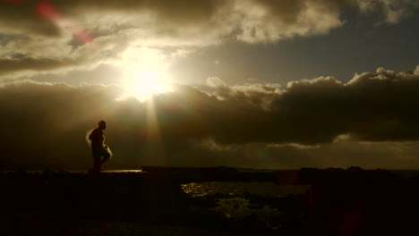 A-gorgeous-shot-as-a-fisherman-walks-in-front-of-the-sunset-with-his-net-in-slow-motion