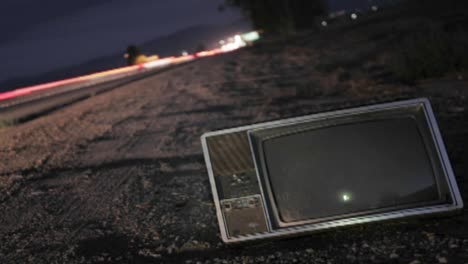 An-abandoned-TV-set-sits-along-a-highway-while-traffic-passes-in-time-lapse