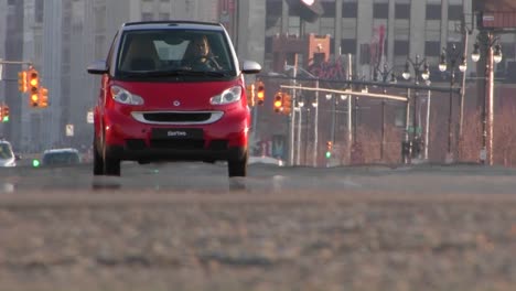 A-man-conduciendo-a-red-Smart-car-through-a-city-1
