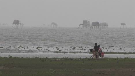 Dos-Niños-Y-Un-Adulto-Cavando-En-La-Arena-En-Una-Playa-Neblinosa-En-Vietnam