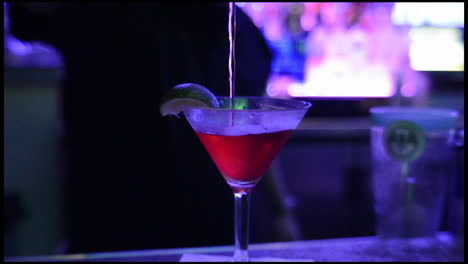 Bartender-pouring-a-shaken-cocktail-into-a-chilled-glass-at-a-nightclub-in-San-Diego-California