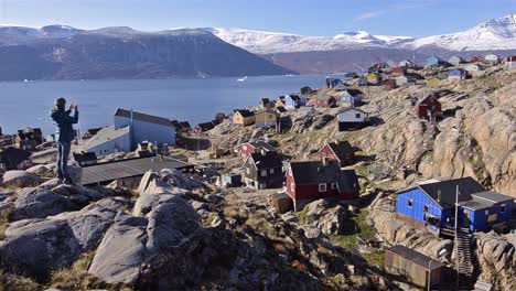 Panning-motion-of-a-hiker-overlooking-colorful-homes-and-Karajak-Fjord-from-Qilakitsoq-in-Uummannaq-Greenland-