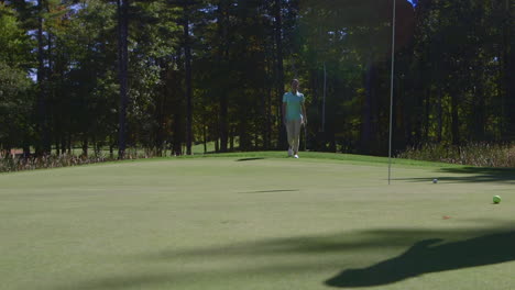 A-female-golfer-chips-a-shot-onto-the-green-at-a-golf-course