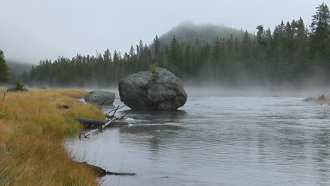 Steam-Rises-From-A-Geothermal-River-On-A-Foggy-Morning-In-Yellowstone-National-Park