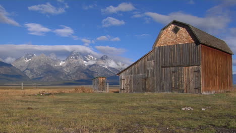 An-Old-Barn-Sits-In-A-Field-With-The-Grand-Teton-Mountain-Range-In-The-Background