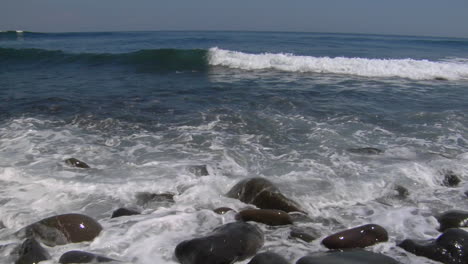 Wellen,-Die-über-Kleine-Glatte-Felsen-Am-Strand-Spülen