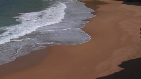 Blue-Green-Waves-Wash-Onto-A-Sandy-Beach