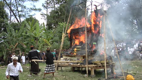 Men-Use-Long-Poles-To-Poke-At-A-Funeral-Pyre-During-A-Cremation-Ceremony-In-Bali