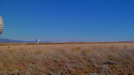Pan-Across-A-Windblown-Field-To-A-Satellite-Dish