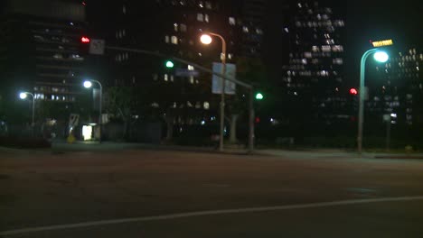 A-Car-Travels-Along-A-Street-At-Night-In-Century-City-Los-Angeles-As-Seen-Through-The-Rear-Window-At-An-Angle