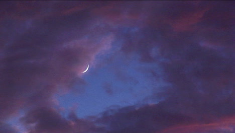 Tinted-clouds-sweep-past-a-crescent-moon-at-golden-hour