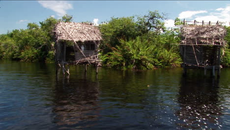Strohgedeckte-Häuser-Auf-Stelzen-Stehen-In-Einem-Tropischen-Flussgebiet