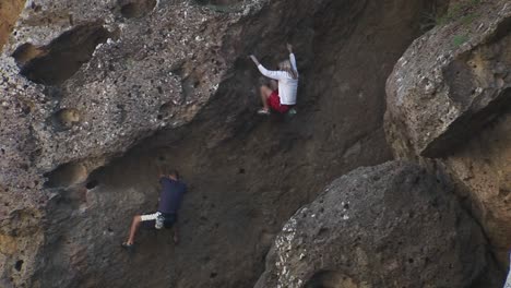 Two-people-are-climbing-up-the-side-of-a-mountain