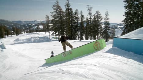 A-snow-boarder-jumps-up-onto-and-slides-down-a-long-ramp
