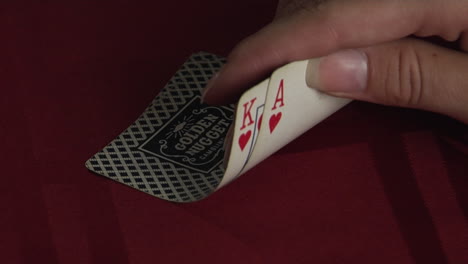 A-hand-turns-up-the-corner-of-two-playing-cards-to-reveal-a-King-and-an-Ace