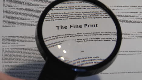 A-magnifying-glass-passes-over-a-paper-to-reveal-the-words-The-Fine-Print