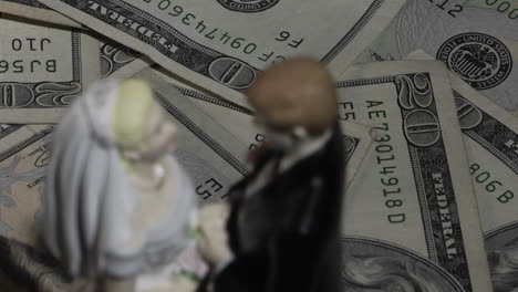 A-married-couple-figurine-stands-amid-twenty-dollar-bills