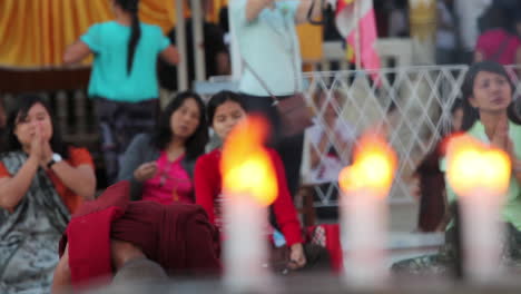 Burmese-people-pray-at-a-Buddhist-temple-with-candles-foreground