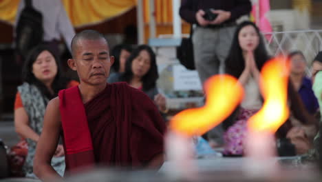 A-Burmese-monk-prays-at-a-Buddhist-temple-with-candles-foreground