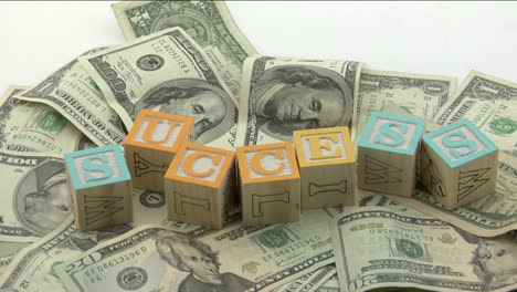 Arranged-wood-blocks-spell-out-the-word-success-on-top-of-a-pile-of-paper-currency