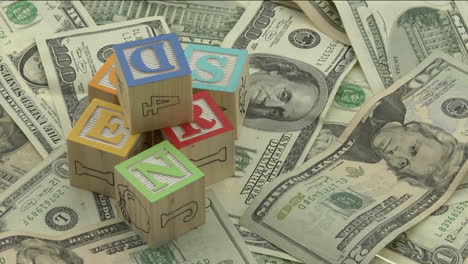 wooden-alphabet-blocks-sit-on-top-of-a-pile-of-money