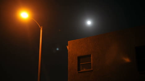 Time-lapse-of-moon-rising-over-a-house-and-street-lamp