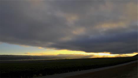 Time-lapse-of-cloudy-sunset-over-a-vineyard