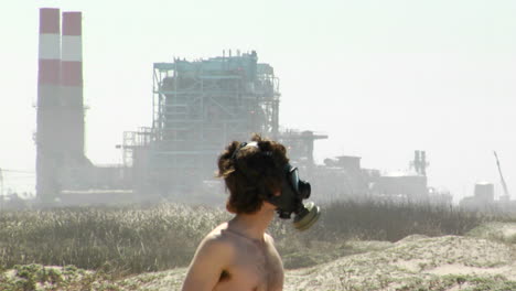 A-man-in-a-gas-mask-stands-in-front-of-a-power-plant
