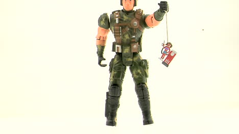 An-Army-action-figure-holds-a-plastic-figurine-of-a-woman-at-a-gas-pump-by-a-string