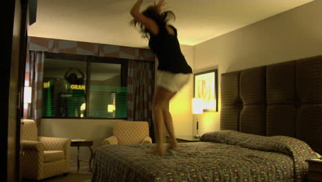 A-young-woman-jumps-on-a-hotel-room-bed