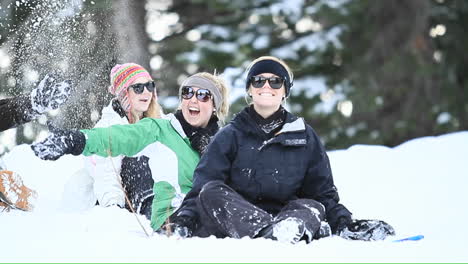 Young-women-on-a-ski-slope-toss-snow-in-the-air