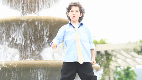 A-boy-in-formal-dress-plays-in-front-of-a-fountain
