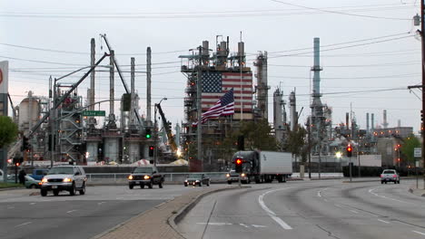 Traffic-passes-by-an-industrial-plant-adorned-with-two-large-American-flags