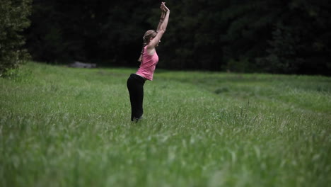 A-young-woman-does-yoga-exercises-in-a-field-of-grass
