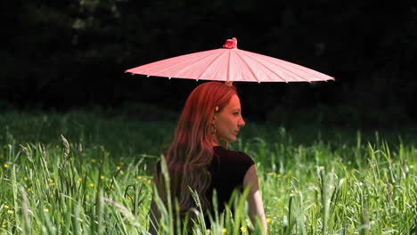 A-woman-with-an-umbrella-is-sitting-in-a-field
