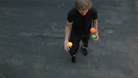 A-man-juggles-three-colored-balls-using-both-his-hands-and-his-feet