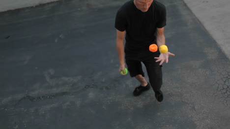 A-man-juggles-three-colored-balls-using-both-his-hands-and-his-feet-1