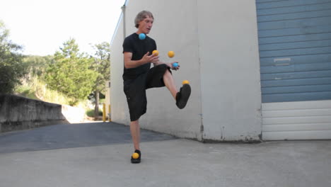 A-man-juggles-five-colored-balls-using-his-feet-as-well-as-his-hands