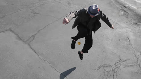 A-man-juggles-an-orange-ball-with-his-foot