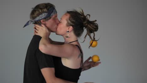 A-man-juggles-balls-behind-his-girl's-back-as-they-kiss