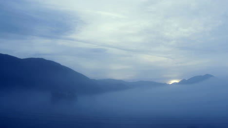 The-sun-shines-behind-a-foggy-mountain-pass