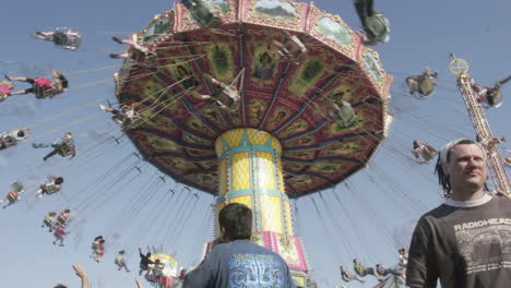 A-swing-ride-at-an-amusement-park-spins-as-visitors-pass-below