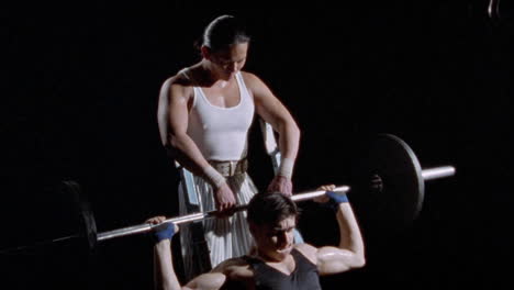 A-man-works-with-a-barbell-with-another-man-assisting-him