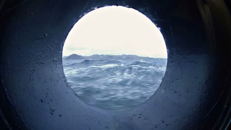 View-through-a-ship's-porthole-while-under-way-in-the-Galapagos-Islands-National-Park-and-Marine-Reserve-Ecuador