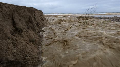 Low-angle-of-Sanjon-Creek-washing-beach-sand-into-the-ocean-after-heavy-rain-in-Ventura-California