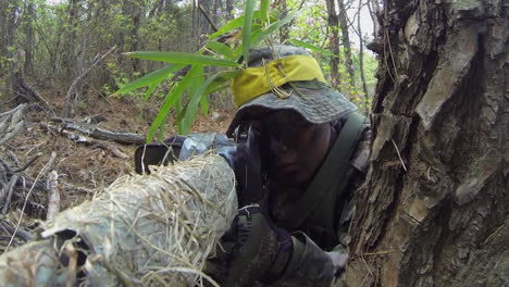 Camouflaged-Sniper-Aims-Gun-From-Forest-Hideout-Position
