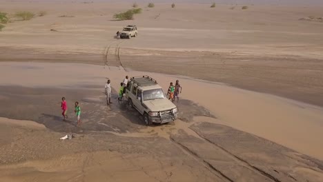 Antenne-Von-Menschen,-Die-Einen-4x4-Jeep-Aus-Einem-Schlammigen-Fluss-In-Den-Wüsten-Von-Dschibuti-Oder-Somalia-Afrika-Schieben-1