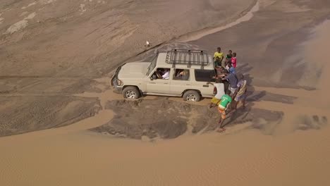 Antenne-Von-Menschen,-Die-Einen-4x4-Jeep-Aus-Einem-Schlammigen-Fluss-In-Den-Wüsten-Von-Dschibuti-Oder-Somalia-Afrika-Schieben-2